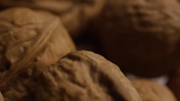 Cinematic, rotating shot of walnuts in their shells on a white surface