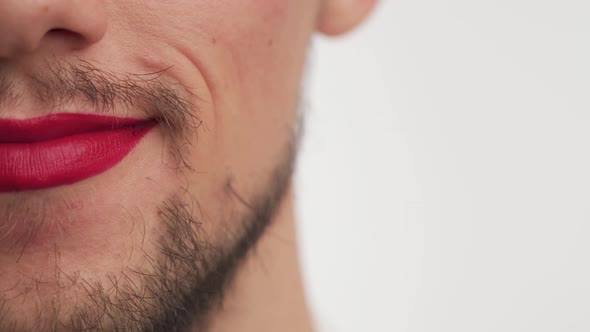 Close up man mouth wear makeup red lipstick on lips. Serious fashion Caucasian boy with beard smiles