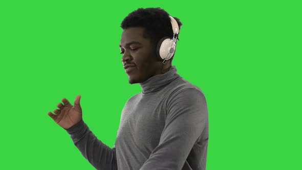 Passionate African American Man Listening To the Music in Headphones and Dancing on a Green Screen