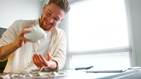 Cheerful guy manager with beard shakes white piggy bank