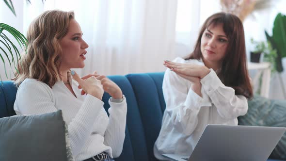 Two Pretty Women Sitting and Talking on Couch