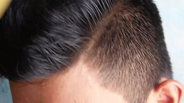 Side View of Man Styling Hair with Comb