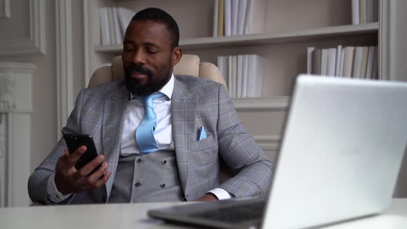 a AfricanAmerican Man in a Plaid Suit with a Tie is Sitting at a Table with a Laptop on a Light