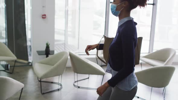 Diverse male and female business colleagues in face masks greeting touching elbows in office