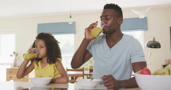 African american father and daughter drinking juice at home