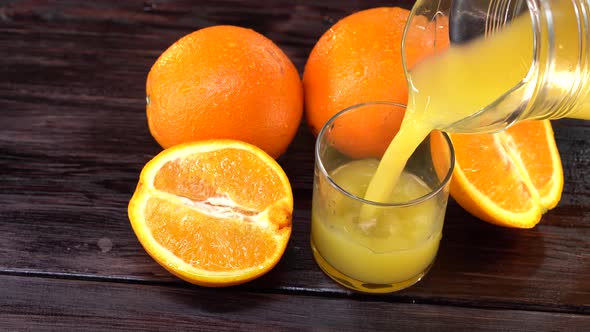 Pour the Orange Juice in a Glass Jar on a Dark Wooden Table