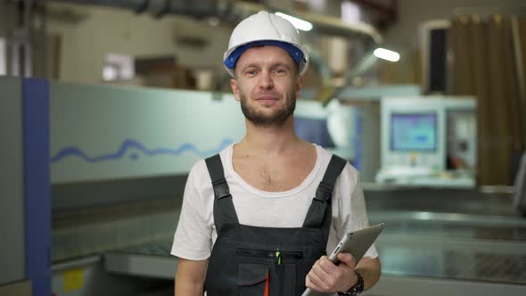 Portrait of Adult Educated Manufacture Male Employee in Helmet Demonstrating Work on Furniture