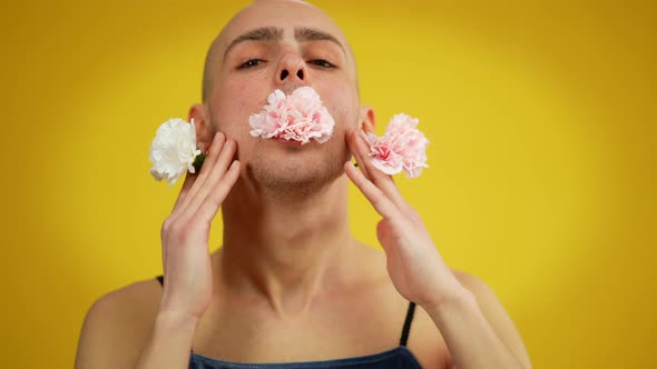Closeup Portrait of Queer Person Holding Flowers in Mouth and Hands Posing at Yellow Background