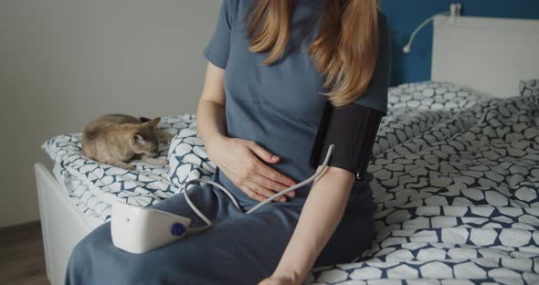 Young Pregnant Woman Checks Blood Pressure with Digital Measuring Device