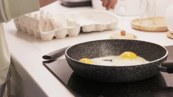 Woman Cooking Scrambled Eggs on Electric Stove Top in the Kitchen Frying Pan with Fried Eggs on