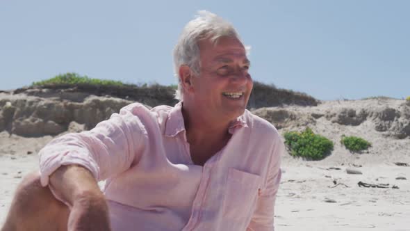 Happy senior caucasian man sitting on the beach enjoying the view