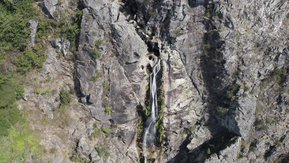 Aerial descending view of waterfall named "Frecha da Mizarela". Focus on its course, Arouca