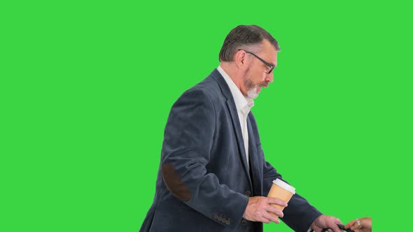 Senior Businessman Walking and Holding in a Hand a Cup of Coffee on a Green Screen Chroma Key