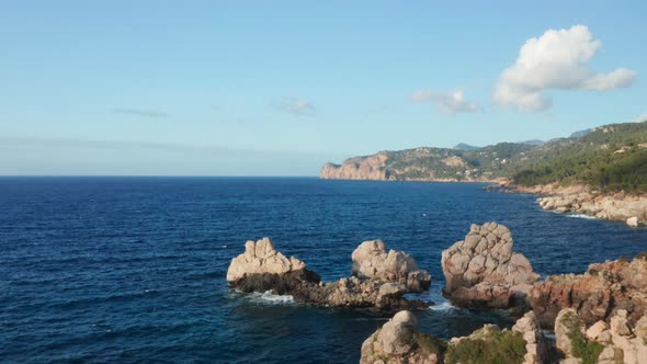 Drone Over Rocks And Blue Of Coastline Under Blue Sky