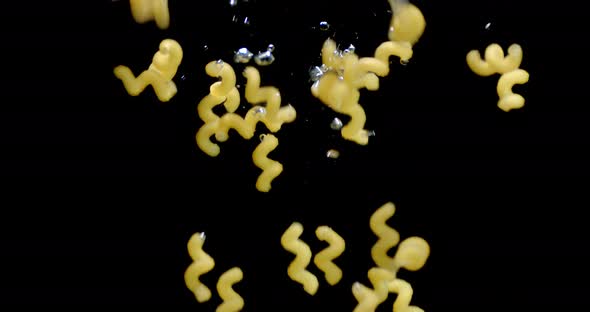 Pasta Dry Cavatappi Falls Under Water with Air Bubbles. 
