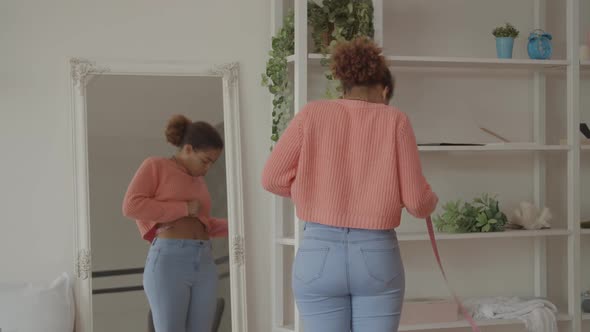 Cheerful African Woman Measuring Her Waist at Home