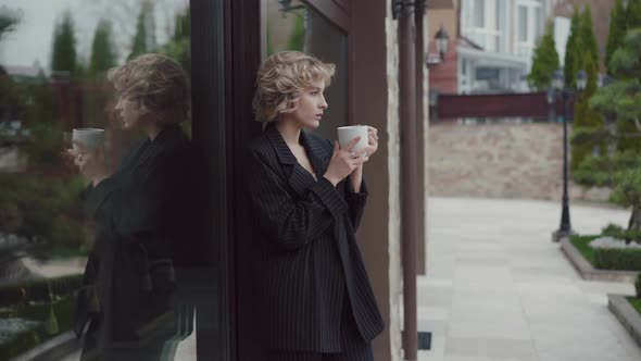 Profile of Beautiful Lady Leaned on Front Door Drinks a Cup of Tea