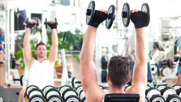 Man Lifting Dumbbells Sitting on Front of Mirror