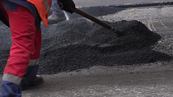 Worker Man Lays Asphalt on a Road Repair Road Paving