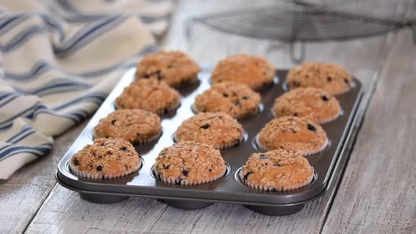 Woman with Freshly Baked Blueberry Muffins in Kitchen.