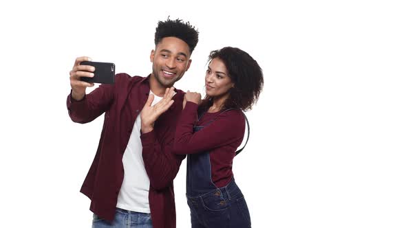 - Happy Cheerful Afro American Couple Making a Selfie and Watching Made Photos Isolated Over White