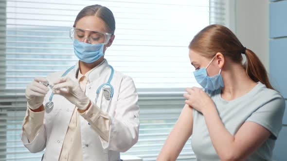 Professional medical nurse in white coat and blue face mask injects