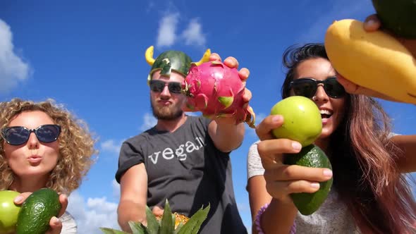 Group of Young People Having Fun With Fruits Against Blue Summer Sky