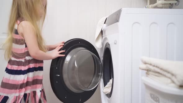 a Cute Little Girl Closes the Washing Machine Door