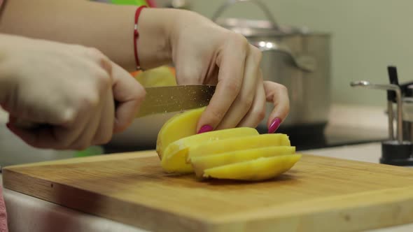 Female Housewife Hands Slicing Potatoes Into Pieces in the Kitchen