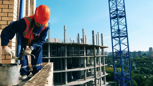 Male Constructor Is Spreading Cement Along the Bricks