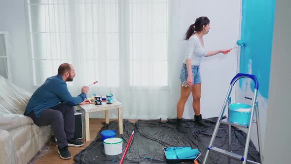 Wife Painting Wall with Roller Brush
