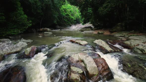 Cascades of a rainforest stream with ferns and mossy rocks in the wilderness of Ko Samui, Thailand