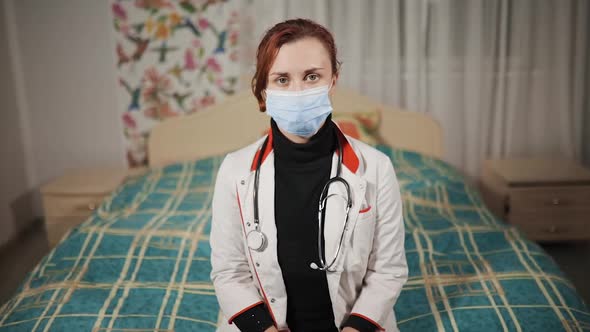 Young Female Nurse or Doctor with Home Visit Sits at Bed