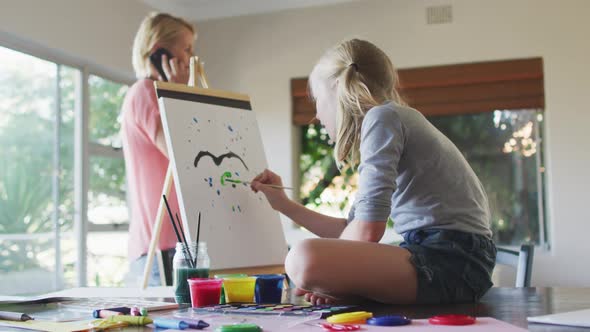 Side view of Caucasian girl painting with her mother at home