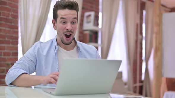 Young Man Celebrating Success on Laptop 