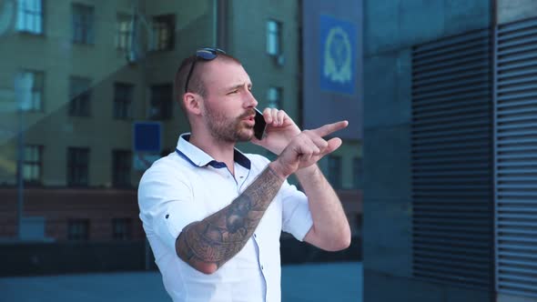 Handsome Businessman Talking on Phone Near office.Young Business Man Speaking on Cellphone Outdoor