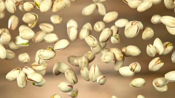 Super Slow Motion Shot of Flying Pistachios After Being Exploded on Wooden Background at 1000Fps.