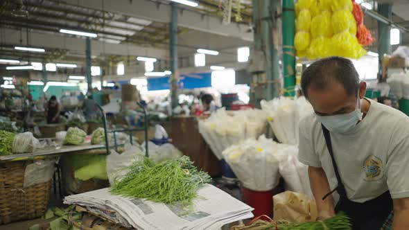 Male Vendor Wearing Protective Mask Selling Fresh Climbing Wattles (Senegalia Pennata) In Vegetable