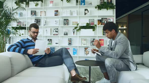 Diverse Men Reading Documents in Office. Side View of Adult Multiracial Men Exploring Paper