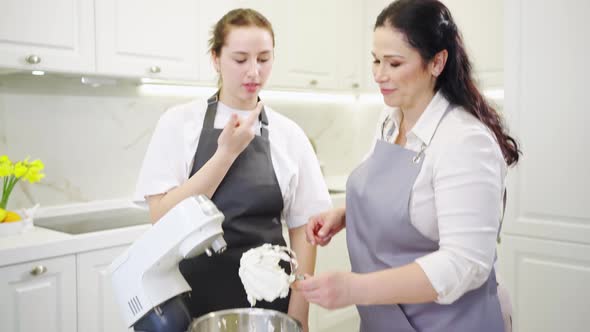 Fun Mom and Daughter Cooked and Tasted Cream or Glaze in Mixer to Dessert