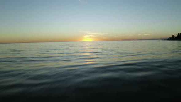 Flying over the ocean at sunset 4K