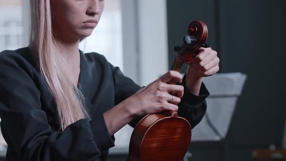 Young Blonde Woman Tuning the Violin