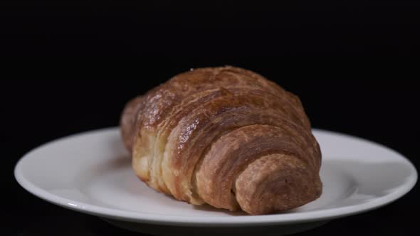 Croissant on white plate rotating in front of camera, Close-up rotates