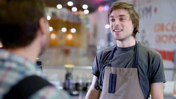 Young Male Barman Is Listening To an Order of Visitor Man in a Bar of Cozy Restaurant in Daytime