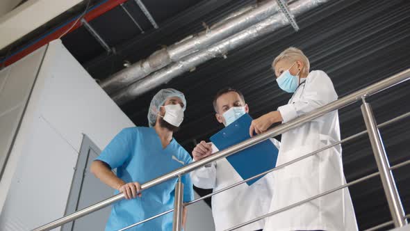 Doctors in Safety Mask Discussing Medical Situation in Hospital Corridor.