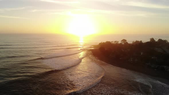 Aerial drone at Rincon Point beach surf break with ocean waves and people surfing at sunset on the b