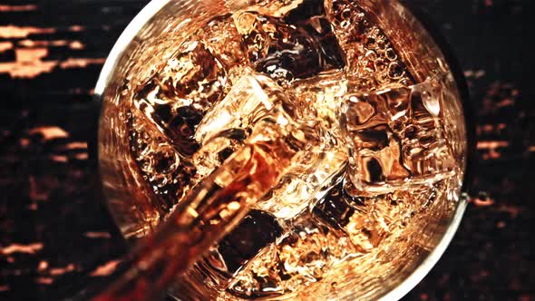 Whiskey is Poured Into a Glass of Ice Cubes