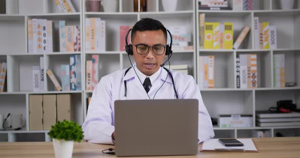 Doctor with headset making conference call on laptop