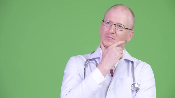 Happy Mature Bald Man Doctor Smiling While Thinking