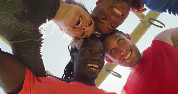 Happy, fit diverse group making a huddle, smiling and touching heads, seen from below